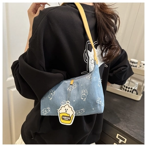 Close-up of denim shoulder bag with bear print and cute cupcake pendant detail
