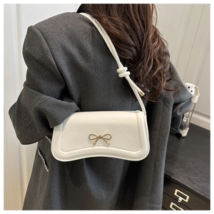 Detailed close-up of white PU leather crossbody bag with a golden metal bow decoration