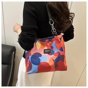 Colorful geometric tote bag with leather strap shown from a side perspective on model