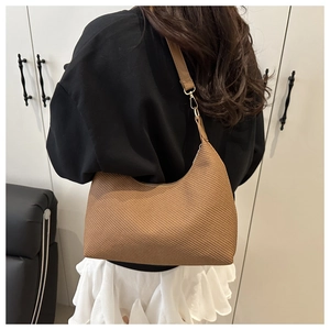 Close-up of brown woven texture hobo bag with gold metal buckle and leather strap
