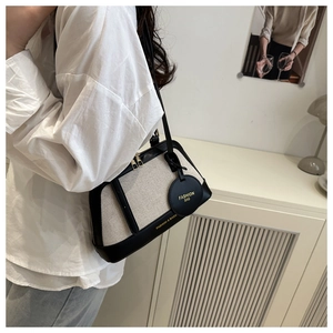 Detail of contrast canvas and leather shell bag with fashion bag tag in home setting