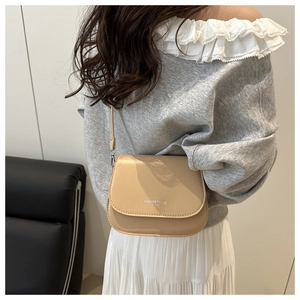 Detail of a beige leather saddle bag with fashion trend text worn by a model