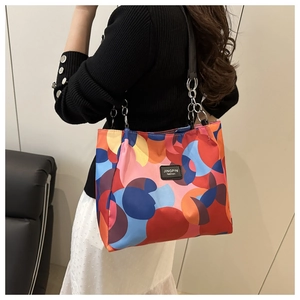 Fashion geometric print tote bag with black leather straps worn by a model in detail