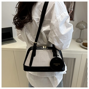 Chic cream canvas and black leather shell bag styled with a modern outfit for daily use
