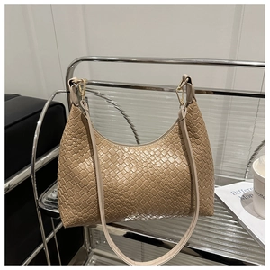 Macro shot of a minimalist beige woven PU leather underarm bag in a cafe setting.