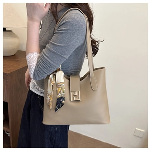Detail of khaki leather tote with gold buckle and decorative silk scarf on handle