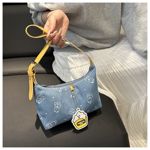 Detail of printed denim underarm bag with yellow leather strap and cute bear patterns