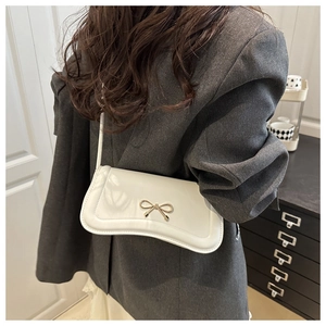 Macro detail of white PU leather bag featuring a elegant gold bow metal fastener