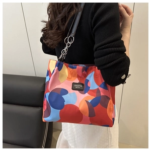 Fashionable underarm bag with abstract colorful patterns and chain strap detail on model
