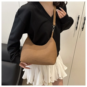 Détail d'un sac porté épaule marron à texture tressée avec crochets dorés et cuir
