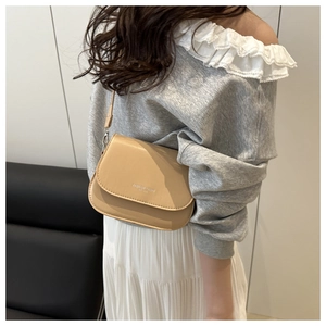 Gros plan d'un sac selle beige avec texte Fashion Trend Est 1993 sur le rabat avant