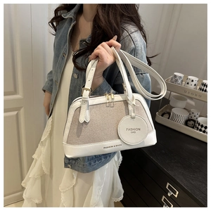 Detail of woven texture handbag with dual handles and round fashion bag charm