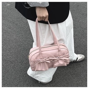 Detail of pink bow shoulder bag featuring dual front pockets in a street style setting