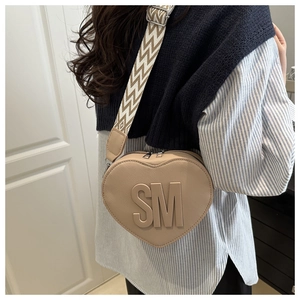 Detail of beige heart-shaped PU crossbody bag with herringbone strap and embossed SM letters