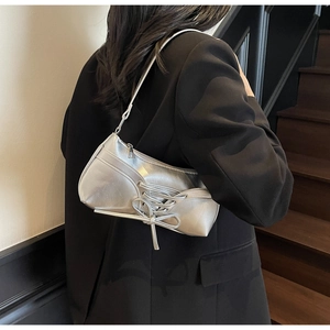 Close-up of silver pleated underarm bag featuring ballet style ribbon lacing details