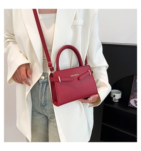 Sac à bandoulière en cuir rouge porté par un mannequin en costume blanc et jean décontracté