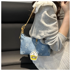 Detail of printed denim underarm bag with cute bear pattern and yellow leather strap