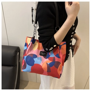 Detail of color-block nylon tote bag with leather logo patch and metal chain strap