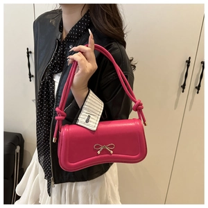 Hot pink baguette bag featuring golden bow detail and decorative knotted shoulder strap