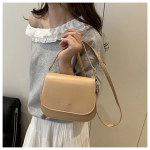 Détail du sac besace beige en cuir avec inscription Fashion Trend EST 1990 gravée