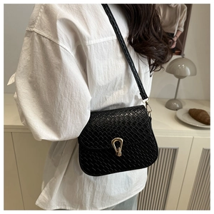 Detail of black woven texture shoulder bag with gold metal lock on a female model