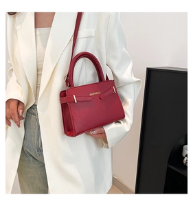 Détail du sac à main en cuir bordeaux avec ferrures dorées et bandoulière fine