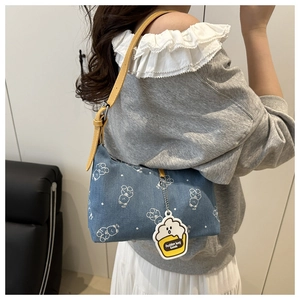 Detail of denim underarm bag with white bear print and yellow adjustable shoulder strap