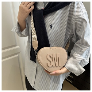 Detail of a beige heart-shaped crossbody bag with SM 3D logo and wide woven strap
