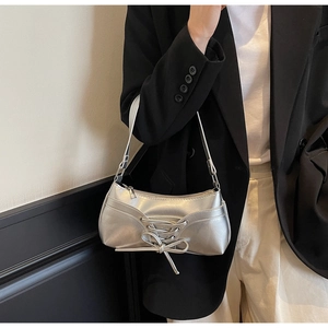 Silver crescent underarm bag with lace-up detail worn over a stylish black blazer