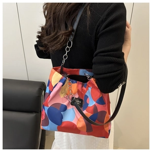 Detail of colorful geometric print shoulder bag with black leather strap and silver chain