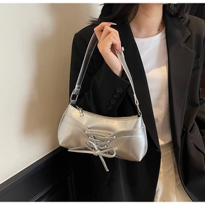 Close-up of metallic silver underarm bag featuring trendy criss-cross lacing and sleek finish