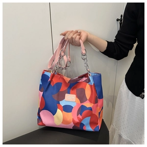 Detail of colorful geometric tote bag with pink handles and silver metal chain link straps