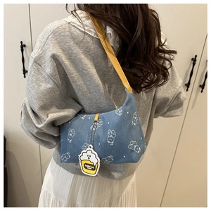 Detail of blue denim hobo bag with white bear prints and yellow leather shoulder strap