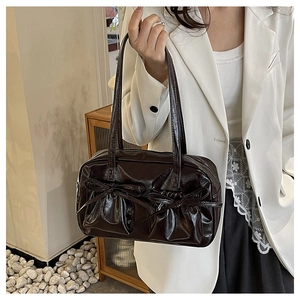 Dettaglio della borsa a spalla marrone caffè con tasche a pieghe e fiocchi decorativi
