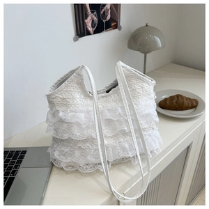 Detail of white lace ruffle tote bag featuring layered textures and slim shoulder straps