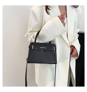 Vue détaillée d'un sac à bandoulière rétro noir avec détails dorés sur un blazer blanc