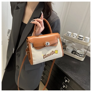 Detail of canvas leather patchwork handbag with floral embroidery and twist-lock closure