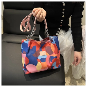 Artistic tote bag with colorful abstract patterns, leather straps, and metal chain detail
