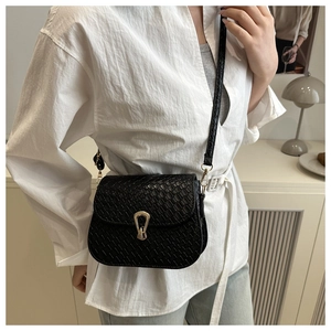 Close-up of black crocodile pattern saddle bag with elegant gold metal buckle detail