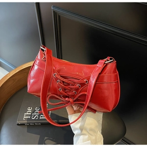 Close-up of a glossy red patent leather underarm bag featuring chic bow tie details