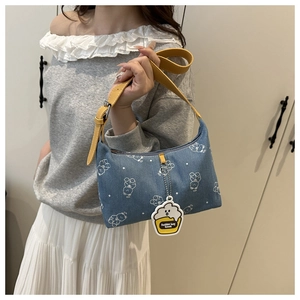 Close-up of denim underarm bag with white bear prints and adjustable yellow strap