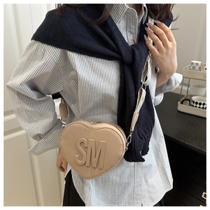 Detail of heart-shaped crossbody bag with SM logo and textured webbing shoulder strap