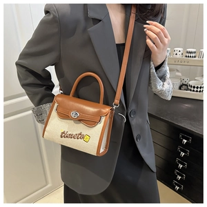 Beige canvas and brown leather crossbody bag styled with a grey blazer and black dress