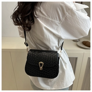 Detail of black crossbody bag featuring crocodile texture and golden horseshoe buckle