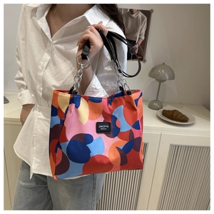 Detail of colorful geometric print tote bag with black leather and silver chain handles
