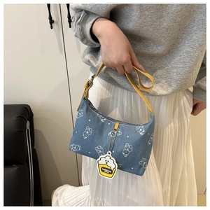 Detail of blue denim shoulder bag with white bear prints and yellow leather handle