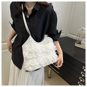 Detail of white lace tote bag featuring multi-layered ruffles and slim shoulder straps