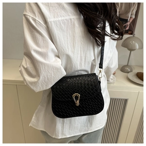 Detail view of black textured faux leather handbag with golden horseshoe buckle