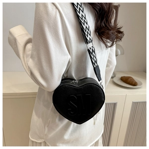 Macro detail of black heart-shaped bag with embossed SM logo and striped woven strap