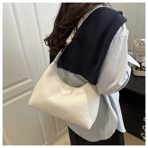Stylish woman wearing a white woven textured underarm tote bag with a striped shirt